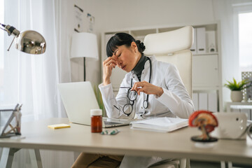 Fototapeta premium Asian female doctor experiencing stress and burnout at workplace