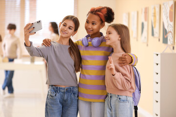 Teenage girls taking selfie in modern art gallery