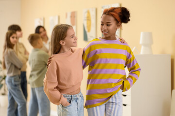 Teenage girls hugging at exhibition in modern art gallery