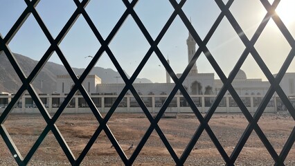 Mosque Building Seen Through Metal Fence with Geometric Pattern and Clear Sky