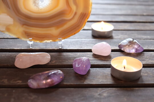 Zen atmosphere with candles and gemstones. Quartz, slice of agate with polished stones and on wood background. Calm vibes with minerals and candles. Meditation and spirituality.	