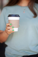 Woman Holding Takeaway Coffee Cup. Young Woman with Takeaway Coffee in Hand. Urban Lifestyle Woman Carrying Coffee Cup. Morning Coffee To Go in Woman's Hand.