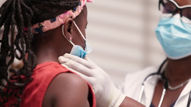 African doctor checking lymph nodes of girl child during pediatric examination