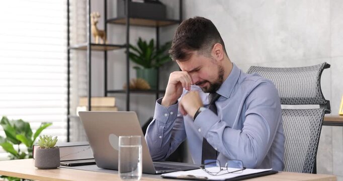 Man feeling fatigue at wooden desk in office