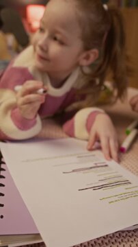 Vertical shot of little kid fully focused on taking home test while her caring and loving parents helping her