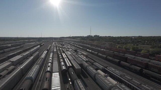 Fort Worth, Texas &ndash; October 19, 2024: Aerial view of a rail yard with multiple parallel train tracks and freight railcars, with the sun visible in the sky creating glare across the scene.