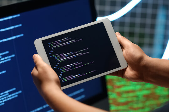 Programmer's hands with modern tablet computer in office, closeup