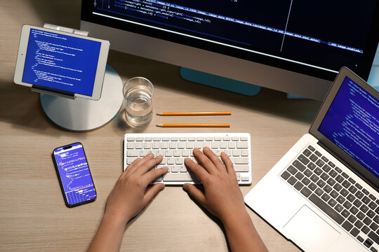 Male programmer working with computer keyboard and mobile phone on wooden background