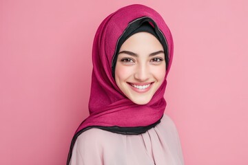 Young woman wearing a bright magenta head covering smiles warmly against a solid pink background