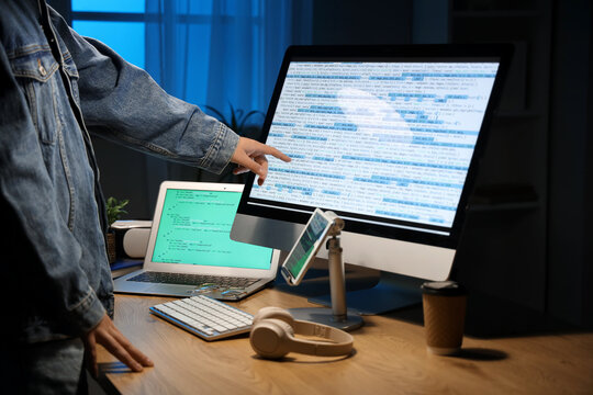 Male programmer pointing at modern computer in office, closeup