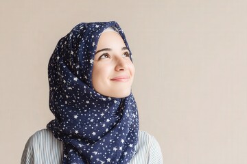 Young woman wearing a patterned head covering gazes upward with a soft smile