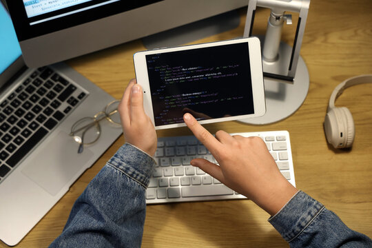 Programmer's hands pointing at modern tablet computer on wooden background