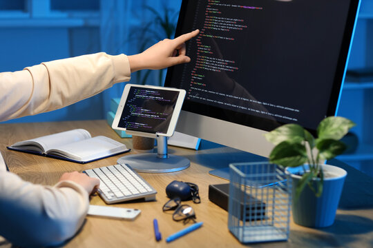 Female programmer pointing at modern computer in office, closeup