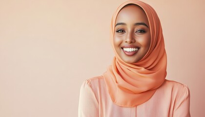 Young adult woman wearing an orange hijab smiles confidently against a soft background