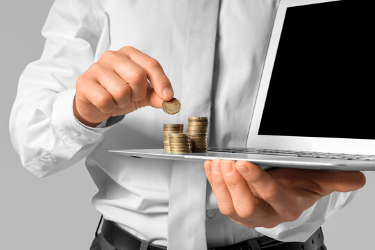 Businessman with laptop and money on grey background, closeup