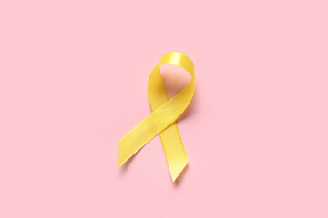 Obraz premium Yellow ribbon on pink background. Childhood cancer awareness concept