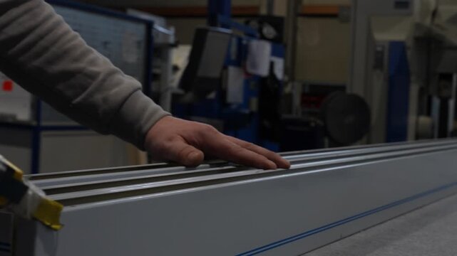 Worker applies adhesive or sealant along a metal profile by hand, creating a continuous bonding line for later assembly, sealing or structural fixation in a manufacturing workflow.