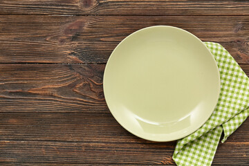 Table setting with plate and napkin on wooden background