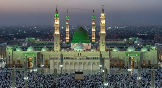 Elevated view of the Prophet's Mosque in Medina at night with green dome and minarets