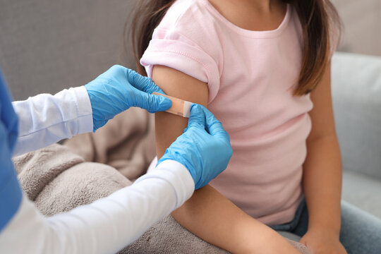 Little girl applying medical patch after vaccination in clinic, closeup