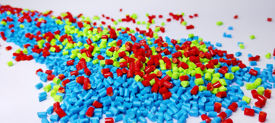 Obraz premium Colorful masterbatch granules are poured into a white background, the video surrounds the cold cutting type masterbatch, as a videography design for an industrial plastic company