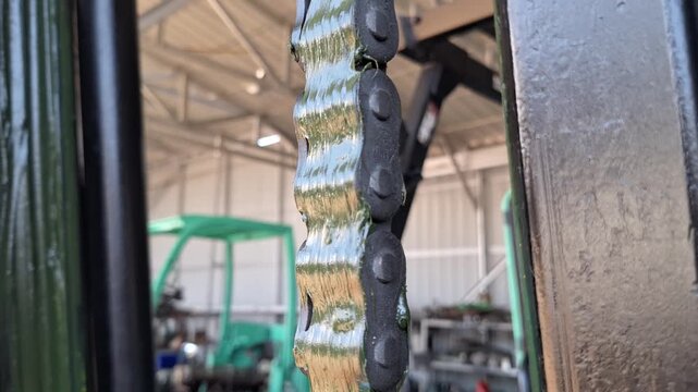Extreme closeup of a heavy duty forklift mast lifting chain with grease, industrial steel roller chain mechanism for warehouse fork lift, technical detail of hydraulic lifting equipment maintenance
