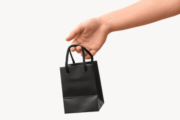 Female hand with small paper shopping bag on white background. Valentine's Day celebration