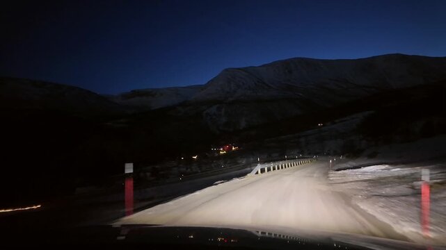 Dashboard camera view from a white sports utility vehicle driving through a winter wonderland at night.
