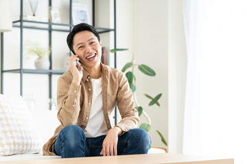 Fototapeta premium リビングで電話するミドルの男性