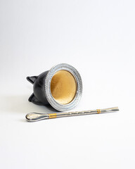 Traditional mate cup made from gourd covered with black leather and smooth metal rim, isolated on white background. Artisan South American drink container, product photo with copy space.