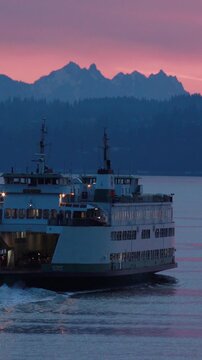 Ferry at sea at sunrise. Washington state ferry in Puget sound with a pink sky over the Cascade mountain range. Vertical design in 9:16 ratio. Smartphone and social media ready.