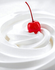 Cherry-topped swirl Glossy red cherry resting on a fluffy white whipped cream swirl. Close-up view