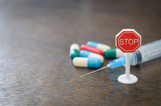 "Colorful Capsules with Syringe and STOP Sign Symbolizing Drug Caution and Medical Awareness