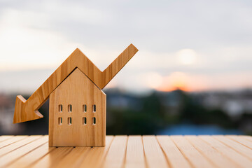 Wooden house model with up and down arrow on roof representing real estate market trend, property price increase and decrease, housing investment risk, financial analysis, and market fluctuation. © sommart