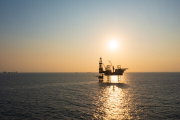 Fototapeta premium Aerial view of offshore jack up rig in a shipyard during sunset for oil and gas exploration and production.