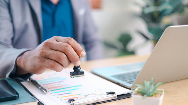 Medical professional stamping approval on healthcare report at modern office desk. Concept of medical insurance approval, document verification, claim processing, compliance review