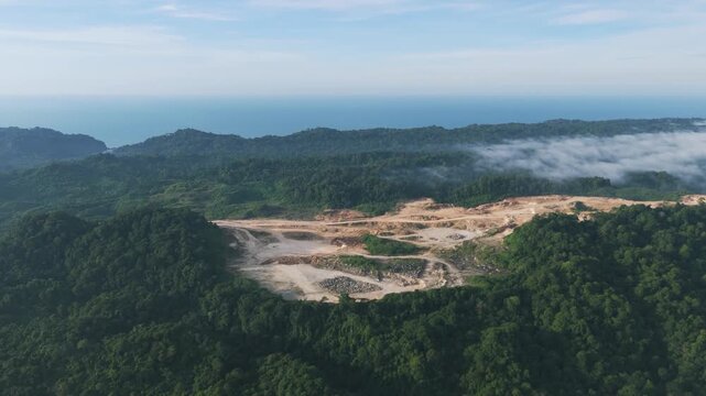 Aerial video close-up of an active limestone quarry on Nusakambangan Island, showing exposed rock surfaces, quarry roads, and excavation zones surrounded by dense tropical forest.