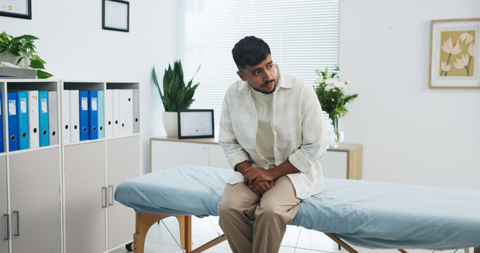 Appointment, healthcare and pain with man in hospital for checkup, discomfort or pressure. Bladder infection, inflammation and medical with patient waiting on bed in clinic for diagnosis or exam