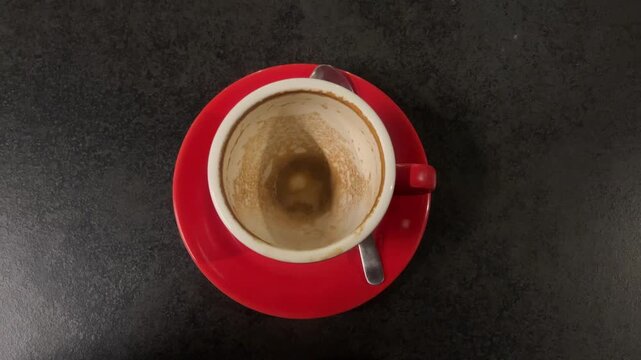 close up view of empty coffee cup after drinking. red cup or mug. Glass table. Cafe, coffe shop, restaurant. Close up view. lefover, leftovers. vertical.