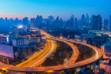 Obraz premium Highway overpass motion with city background cityscape with a network of highways. Top view of skyscraper and high-rise buildings at night.