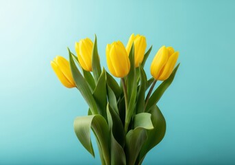 Naklejka premium A bouquet of bright yellow tulips on a teal colored background with green leaves