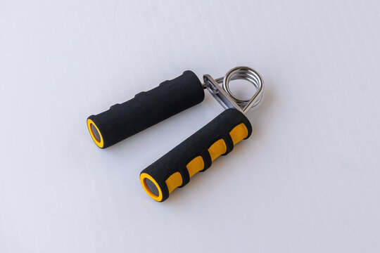 Hand grip strengthener with black and yellow foam handles on a white background. This forearm exerciser and wrist strength training equipment is a perfect tool for fitness and physical therapy