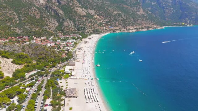 Oludeniz, Turkey. Aerial drone view of a paraglider with blue parachute flying over Oludeniz Beach and the Blue Lagoon, Babadag Mountain in the background, summer.. Aerial View