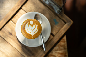 Cup of coffee latte art on wood table.