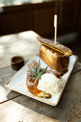 Bread toast with caramelized banana and ice cream on a wooden table.