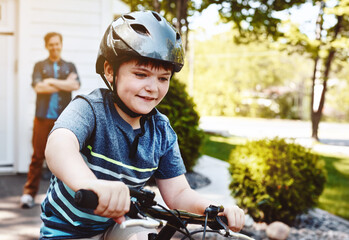 Obraz premium Neighborhood, happy and dad with boy on bicycle for cycling, learning to ride and exercise. Family home, holiday and father watching kid on bike for development, hobby and outdoor activity on weekend