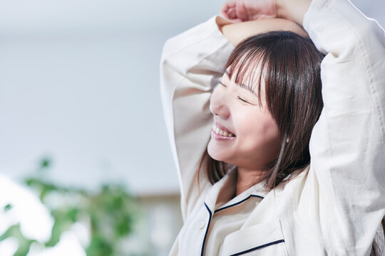 ベッドルームでストレッチをするパジャマを着た若い女性