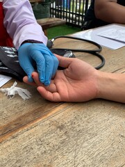 Medical professional wearing blue gloves inserting needle into patient. Person lying on medical chair with intravenous drip attached to their arm for blood transfusion or donation.