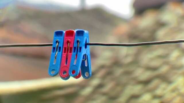 Blue and red plastic clothespins hanging on a wire fence