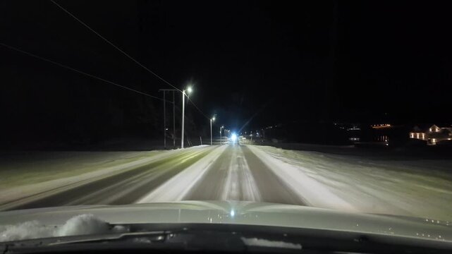 Dashboard camera view from a white car driving through the rural winter landscapes of Averoeya, Norway, at night.